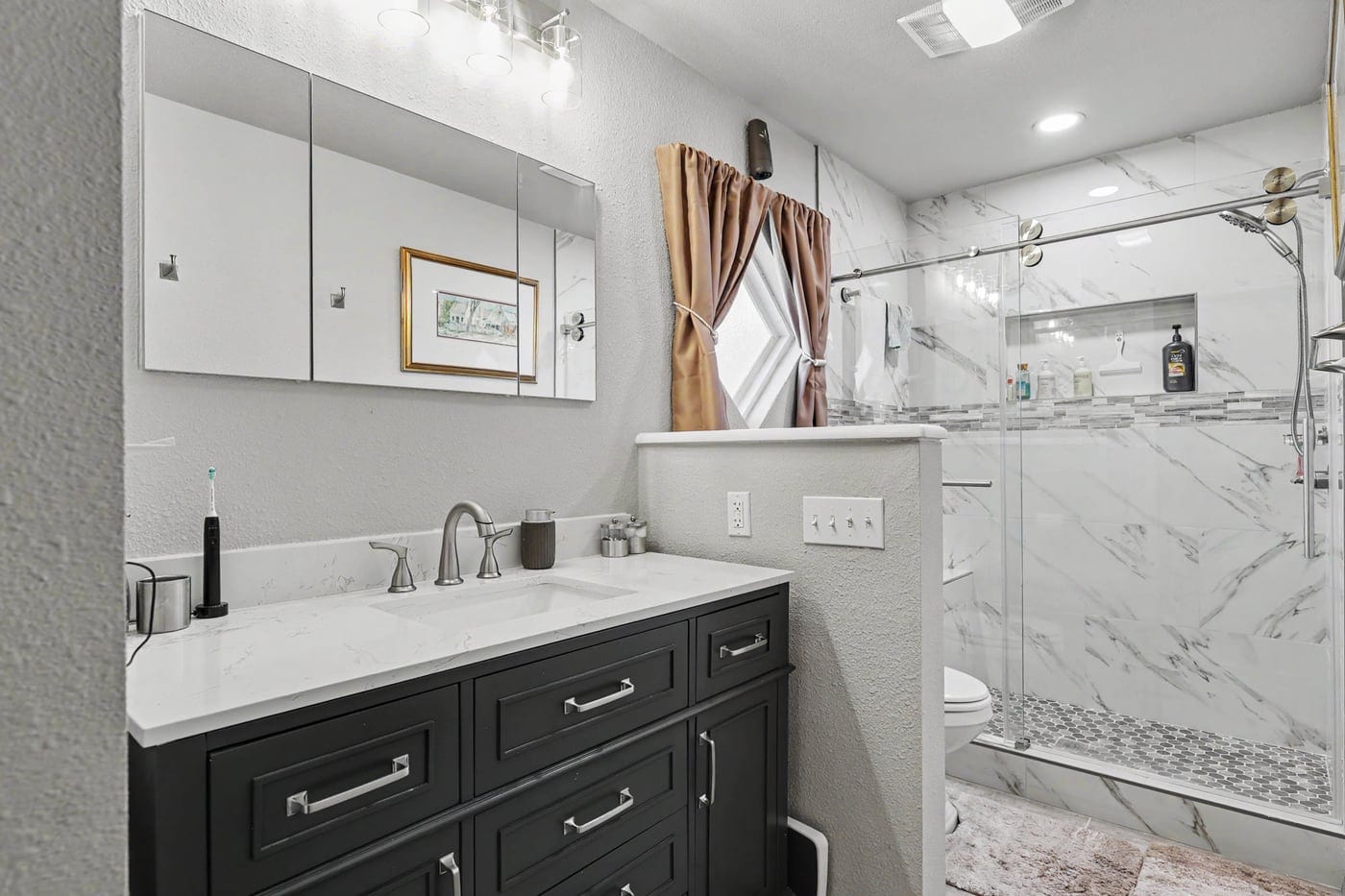 Bathroom remodel in Edmond, OK with charcoal vanity and marble-look tile shower