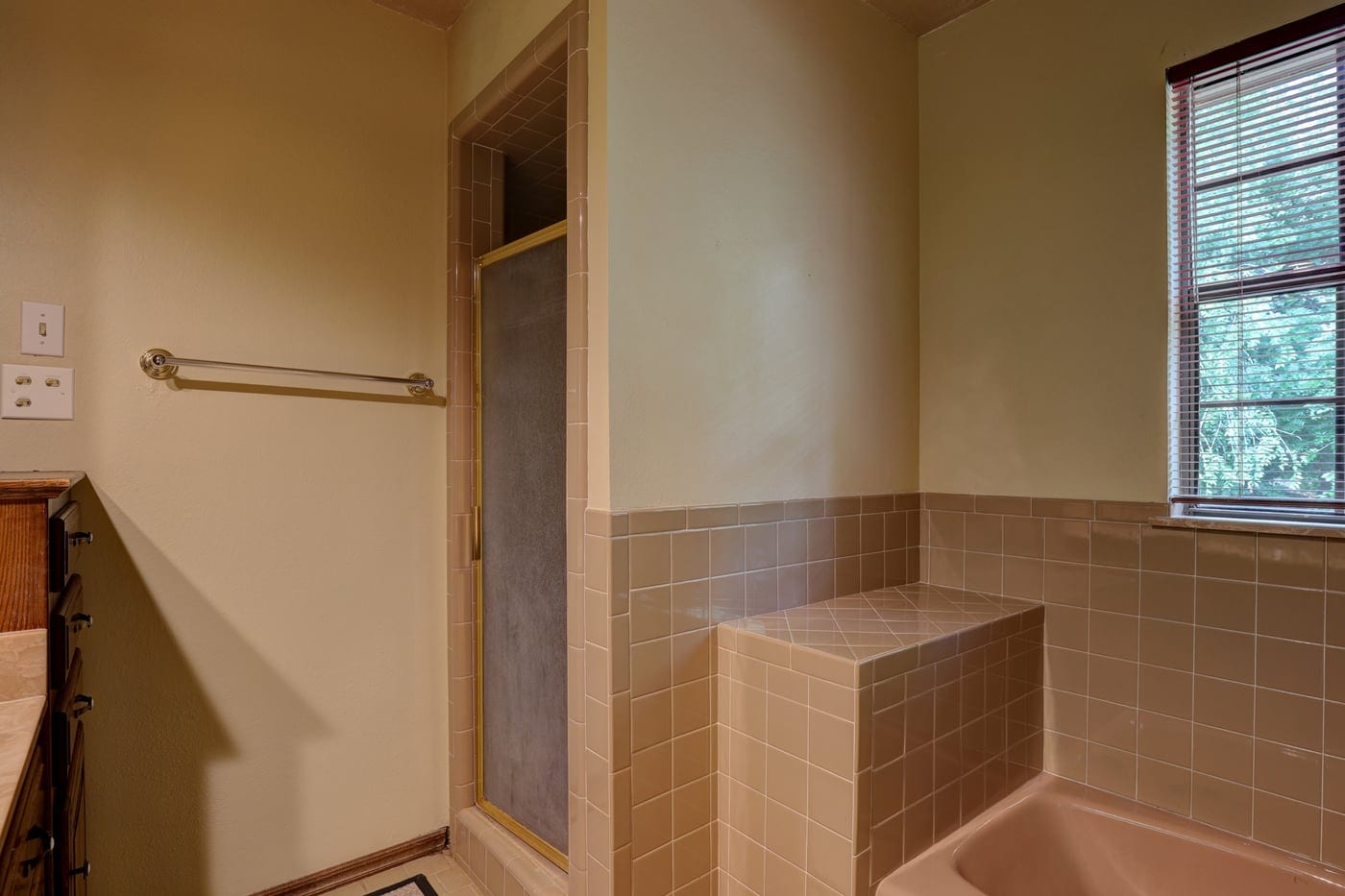 Old shower with framed door and tile surround before the remodel